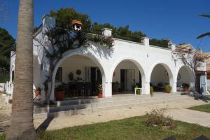 a white building with arches and a palm tree at VILLA LOS TRES SOLES in Les tres Cales