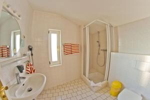 a white bathroom with a sink and a shower at Fährblick - Pension direkt am Wasser in Sassnitz