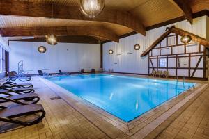 a large swimming pool in a building with chairs around it at Sport- & Vital-Resort Neuer Hennings Hof in Perleberg