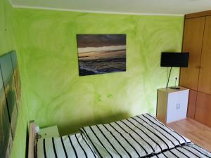 ein grünes Zimmer mit einem Bett und einem Bild an der Wand in der Unterkunft Ferienwohnung Gravemeier in Ladbergen