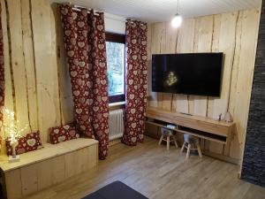 ein Wohnzimmer mit einem Flachbildfernseher an der Wand in der Unterkunft La Pinéguette maison 12 personnes spa 6 pers décoration chalet sauna 4 pers in La Bresse