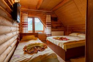 a bedroom with two beds in a log cabin at Gostynnyi Dvir Burkut in Verkhovyna