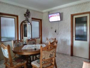 tavolo da pranzo con sedie e TV a parete di Diófás Vendégház Mórahalom a Mórahalom