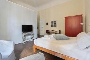 a bedroom with a large white bed and a television at Apt. Fiordaliso - Pauline Suites, Palazzo Borghese in Florence