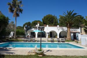 a villa with a swimming pool and palm trees at VILLA LOS TRES SOLES in Les tres Cales