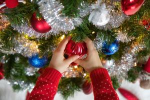 Un niño tiene un adorno rojo en un árbol de Navidad. en Hotel La Palù en Pinzolo