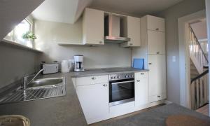 a kitchen with white cabinets and a sink at Stadtwohnung zur großen Buche in Leer