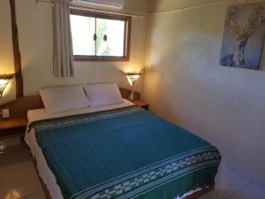 a bedroom with a bed with a blue blanket and a window at Pousada Casa Na Bolom in Barra Grande