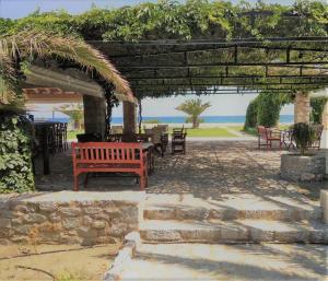 a red bench under a pergola with a view of the ocean at Ktima Petalea in Gythio