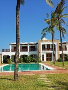 a villa with a swimming pool and palm trees at The Sultan Palace in Mombasa