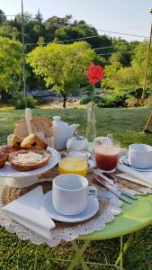 una mesa de picnic con comida y café y un jarrón con una rosa en Posada Casa de Piedra en Los Reartes