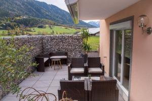 eine Terrasse mit Stühlen, Tischen und einer Steinmauer in der Unterkunft Ferienwohnung Maric in Oetz