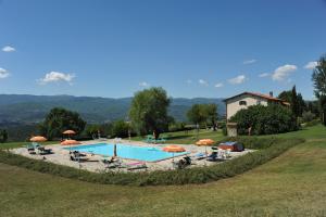 uma piscina com cadeiras e guarda-sóis num campo em Fattoria di Belvedere em Poppi