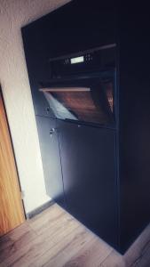a black oven in a kitchen with a wooden floor at Arber Apartments - Zwieslerwaldhaus in Lindberg
