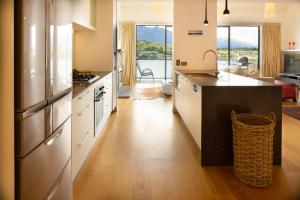 a kitchen with a stove, refrigerator, sink, and dishwasher at Villa Del Lago in Queenstown