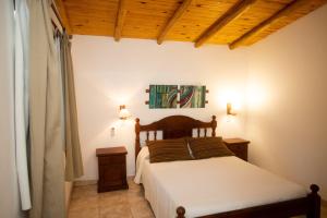 1 dormitorio con cama y techo de madera en Cabañas El Vallecito en Villa del Dique