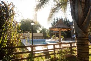 una piscina con sombrilla y una palmera en Cabañas El Vallecito en Villa del Dique