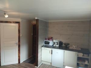 a kitchen with white cabinets and a microwave at Summer haus in Syreflot
