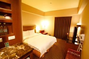 um quarto de hotel com uma cama e uma televisão em Kindness Hotel Taitung Branch em Taitung City