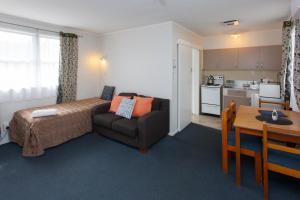 Otorohanga & Waitomo Motels في أوتوروهانغا: غرفة نوم بسرير واريكة وطاولة