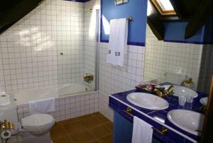 a blue and white bathroom with two sinks and a toilet at Hostal Meson Leira Antiga in Cedeira