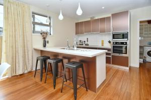 a kitchen with a counter and stools in it at Clyde 106 - Christchurch Holiday Homes in Christchurch