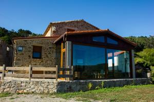 kamienny dom z dużym szklanym oknem w obiekcie Casa das Fiadeiras de Nemiña con Jacuzzi w mieście Nemiña