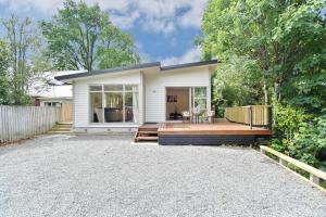 Clyde 106 - Christchurch Holiday Homes في كرايستشيرش: منزل مع شرفة خشبية في الفناء الخلفي