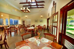 uma sala de jantar com mesas e cadeiras num restaurante em Triveny River Palace em Alappuzha