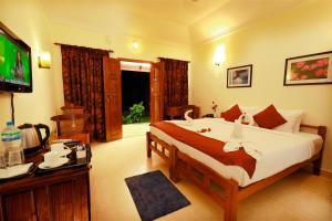 um quarto com uma cama grande e uma televisão em Triveny River Palace em Alappuzha