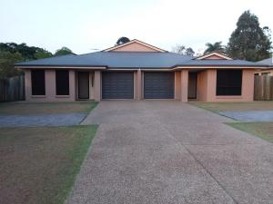 a house with two garage doors and a driveway at Banksia Apartment in Maryborough