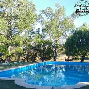 a blue swimming pool in a park with trees at Cabaña de Montaña, La Casita Mina Clavero CBA in Mina Clavero