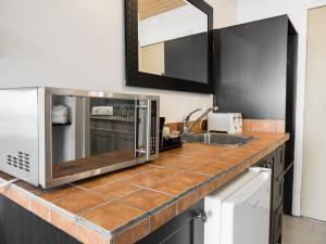 a kitchen counter with a microwave and a sink at Motel Classique in Joliette