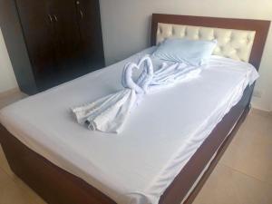 a bed with white sheets and a towel on it at Sensacional Apartamento Reserva Peñon Girardot in Girardot