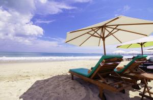 zwei Stühle und ein Sonnenschirm am Strand in der Unterkunft KELAN-TEL BALI in Jimbaran