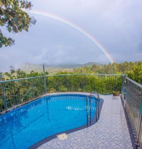 a rainbow in the sky over a swimming pool at Chrissie's Hotel in Thekkady