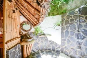 a bathroom with a stone wall with plants on it at Le Bamboo Bali in Uluwatu +64 photos