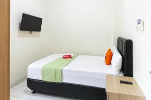 um quarto com uma cama num quarto com uma televisão em RedDoorz Syariah near Purwosari Train Station em Surakarta