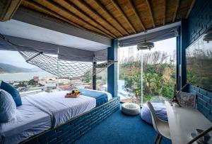 ein Schlafzimmer mit einem Bett und einem großen Fenster in der Unterkunft Mira Bãi Xếp Quy Nhơn - The Hidden Jewel in Quy Nhon