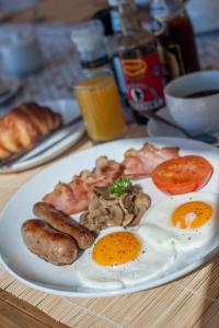 a plate of breakfast food with eggs sausage and mushrooms at Plett Beachfront Guest House in Plettenberg Bay
