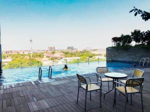 a table and chairs next to a swimming pool at Elegant Studio Apartment at Tamansari Papilio By Travelio in Surabaya