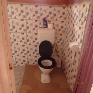 een kleine badkamer met een toilet met een zwarte stoel bij Classixx Inn in Nausori