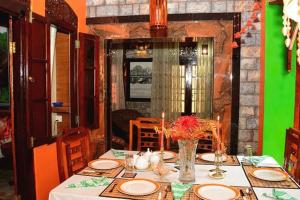 Linda Cottage في غالي: طاولة طعام مع طاولة قماش بيضاء وجدار أخضر