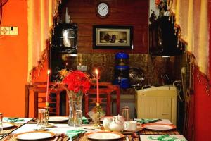 a table with plates and a vase of flowers on it at Linda Cottage in Galle