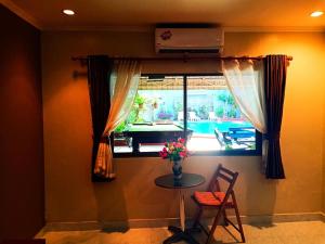 una habitación con una mesa y una ventana con un jarrón de flores en Southern Star Resort, en Norte de Pattaya