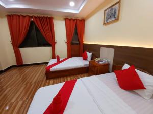a hotel room with two beds and red curtains at Capitol One in Phnom Penh