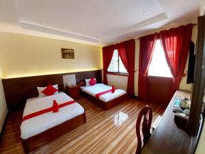 a hotel room with two beds and red curtains at Capitol One in Phnom Penh
