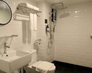 La salle de bains est pourvue d'un lavabo, de toilettes et d'une douche. dans l'établissement Le Embassy Hotel Georgetown, à George Town