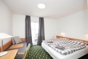 a bedroom with a bed and a desk and a window at Hotel Osted in Lejre