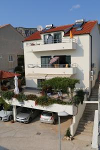 a large white building with cars parked in a parking lot at Apartments Stipe Plazibat in Hvar